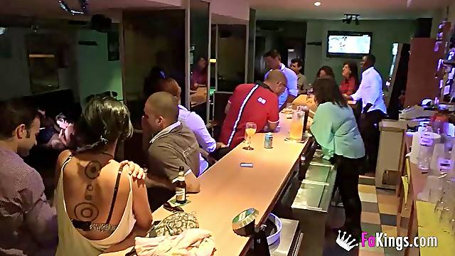 A party girl with tattooes gives blowjob to 2 guys in public